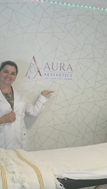 Laura beside the Aura Aesthetics sign inside the Stoney Creek clinic